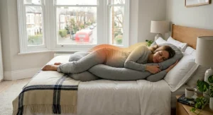 Exploded view of a C-shaped pregnancy pillow showing the removable, machine-washable cover.