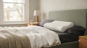 Premium therapeutic pillow styled cleanly on a crisp white duvet in a sunlit bedroom, ready for bedtime use.