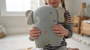 A cheerful set of three different animal-themed kids character pillows displayed on a shelf.