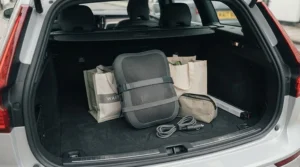 Compact massage pillow for a car seat neatly packed away inside a hatchback car boot alongside shopping bags.