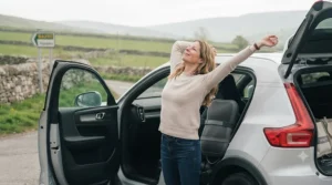 Driver stretching comfortably after a long-distance drive, aided by regular use of a massage pillow for a car seat.